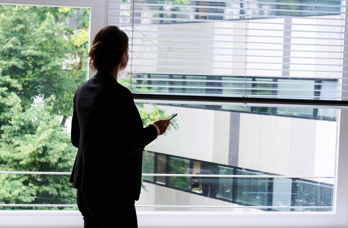ARCHIV - 09.07.2021, Berlin: ILLUSTRATION - Eine Frau steht in einem Bürozimmer am Fenster und telefoniert über ein Headset. (gestellte Szene) Die Topetagen öffentlicher Unternehmen in Deutschland wer ...