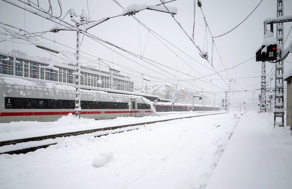 02.12.2023, Bayern, München: Ein ICE steht neben einem verschneiten Gleis und Bahnsteig am Hauptbahnhof. Der Zugverkehr von und zum Hauptbahnhof wurde vorübergehend eingestellt. Schnee und Eis haben i ...