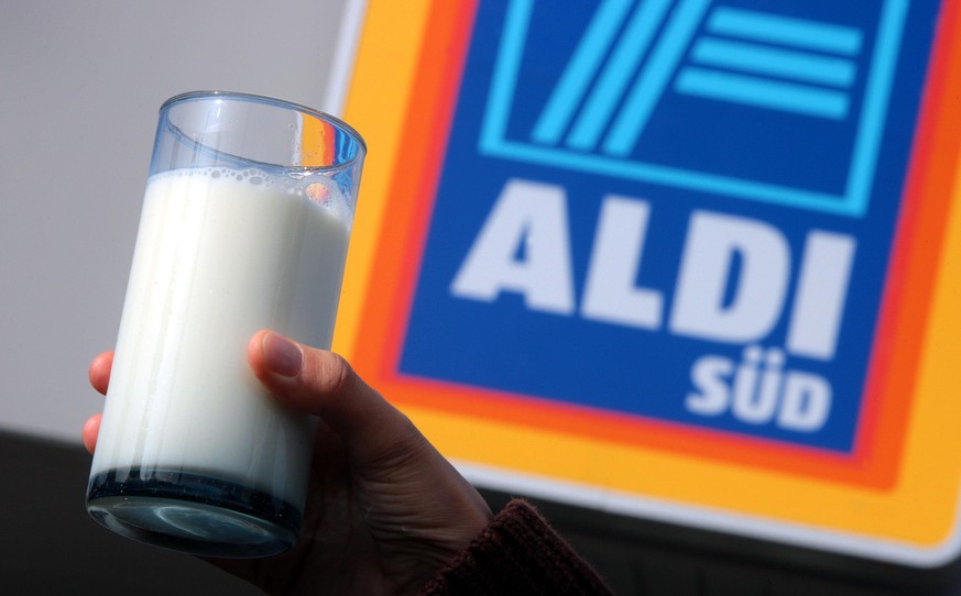 Eine Hand hält am Freitag (18.04.2008) in Kaufbeuren (Schwaben) ein Glas Milch vor dem Logo einer Aldi-Filiale hoch (Illustration zum Thema Milchpreise bei Aldi). Ab kommenden Montag soll bei Aldi lau ...