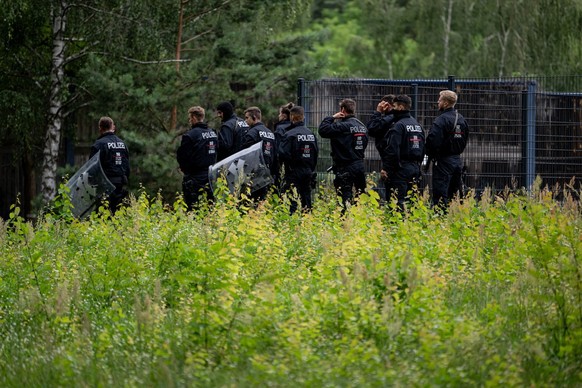 21.07.2023, Brandenburg, Kleinmachnow: Polizisten laufen im Bereich der südlichen Landesgrenze von Berlin. Ein gefährliches Wildtier soll in der Nacht zum Donnerstag in Brandenburg entlaufen sein und  ...