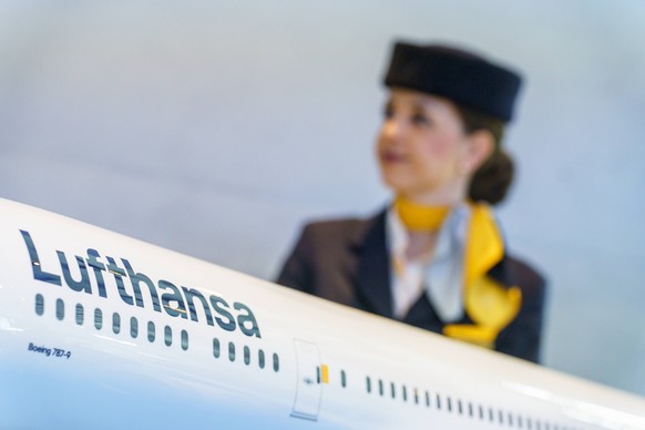 ARCHIV - 03.03.2023, Hessen, Frankfurt/Main: Eine Flugbegleiterin steht hinter einem Modell einer Lufthansamaschine. Bei der Lufthansa ist f�r das Kabinenpersonal als letzte gro�e Besch�ftigtengruppe  ...