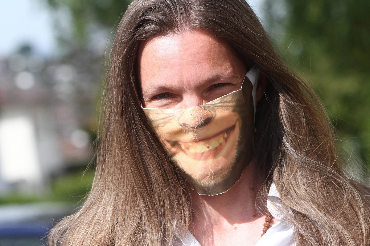 Frau trägt eine selbst gebastelte Mund- und Nasenschutzmaske mit Aufdruck eines lachenden Schimpansen, model released *** Woman wearing a homemade mouth and nose protection mask with imprint of a laug ...