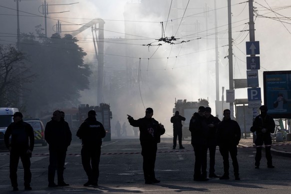 KYIV, UKRAINE - OCTOBER 17: Members of the Ukrainian police force stand guard next to smoke as Ukraine&#039;s capital is rocked by explosions during a drone attack in the early morning on October 17,  ...
