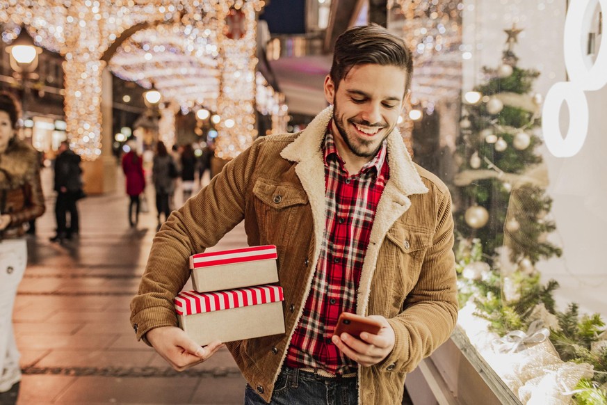 Portrait of a young man holding gift boxes Christmas shopping