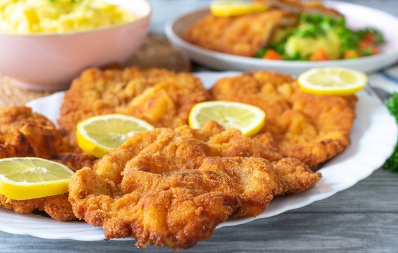 A plate of fresh fried and homemade pork schnitzels on a plate. Served for dinner with lemon slices. closeup view with selective focus on forground