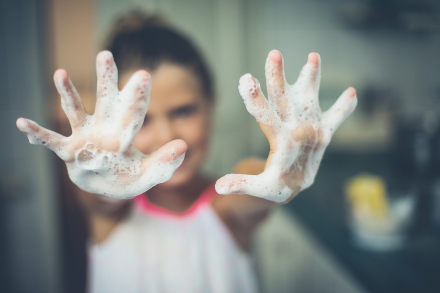 Hands of a little girl of foam. Close up. Copy space. Focus is on hands.