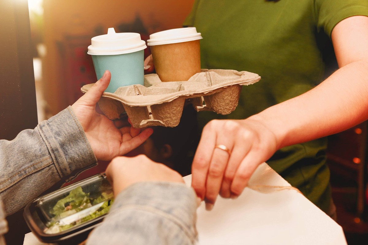 Pizza delivery girl gives carton box to female customer on the doorstep Pizza delivery girl gives carton box to female customer on the doorstep, delivering service. Courier from pizzeria and woman ind ...