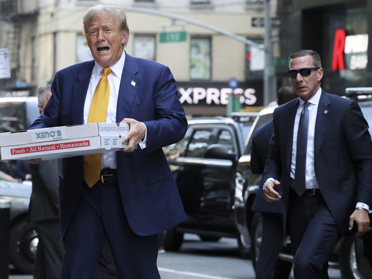 Former President Donald Trump carries boxes of pizza upon arriving at a New York City fire house to meet with firefighters, Thursday, May 2, 2024, in New York. (AP Photo/Yuki Iwamura)