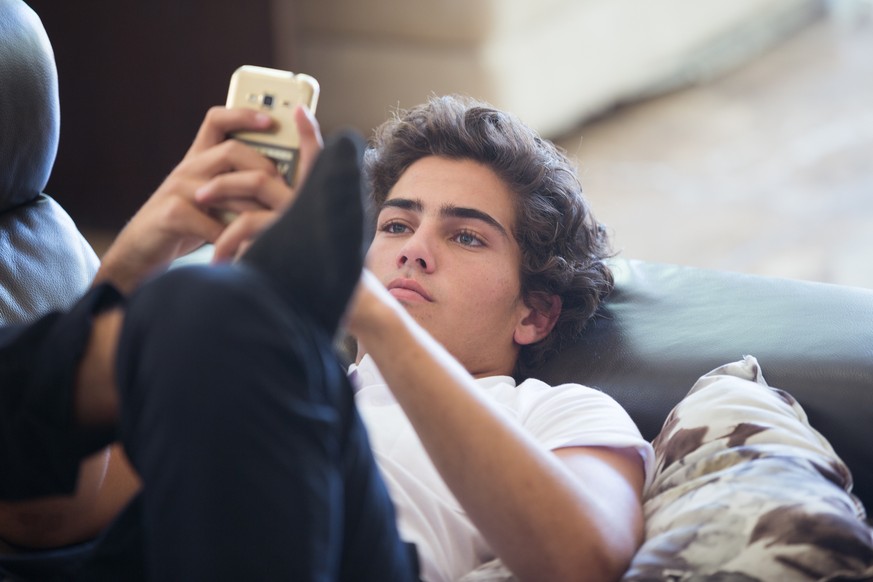 Young Man on Sofa with Cell Phone