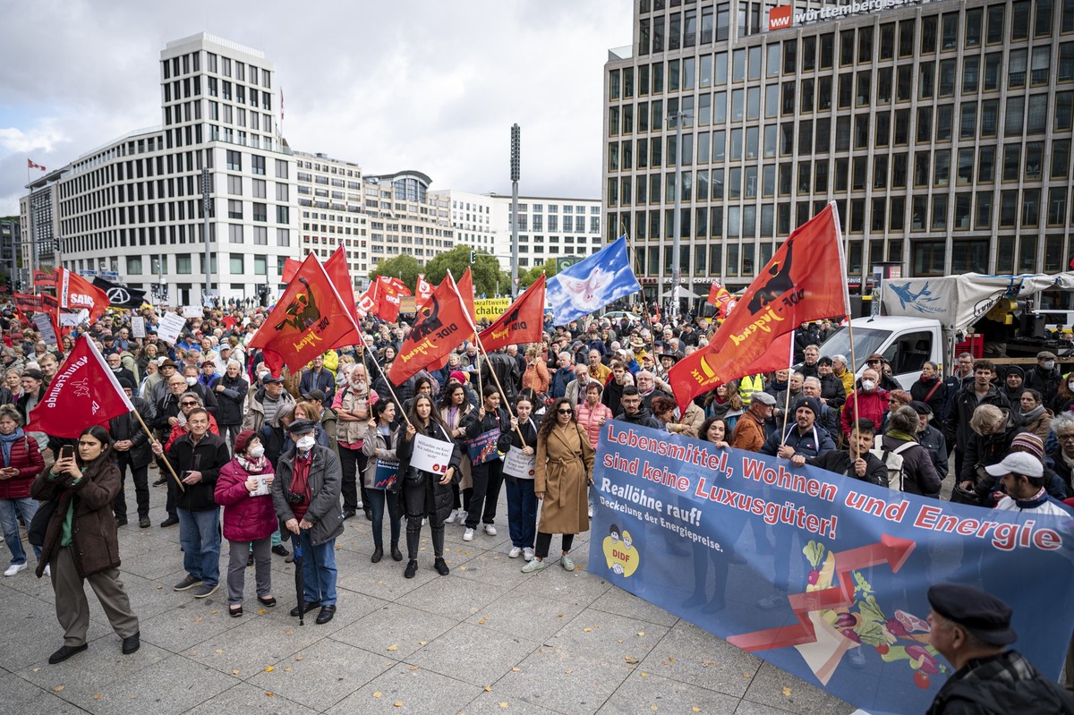 03.10.2022, Berlin: Teilnehmer stehen auf der Demonstration «Heizung, Brot & Frieden! Protestieren statt frieren» am Potsdamer Platz mit Fahnen und Plakaten. Die Demo wird von einem Bündnis versch ...