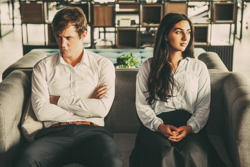 Resentful colleagues looking away from each other because of misunderstanding. Unhappy business people being quarreling and sitting on one sofa. Conflict concept