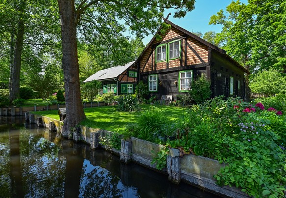 18.05.2022, Brandenburg, Lehde: Traditionelle Holzh�user stehen an einem Flie� (Wasserweg) im Spreewalddorf Lehde. Foto: Patrick Pleul/dpa +++ dpa-Bildfunk +++