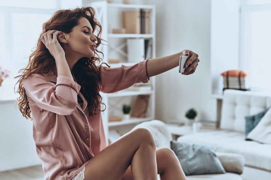 Attractive young women puckering while taking selfie at home