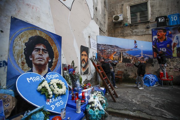 Men hang on a wall a giant photo of the Gulf of Naples with soccer legend Diego Maradona topping the Vesuvius volcano, at the popular &quot;Quartieri Spagnoli&quot; neighborhood, in Naples, Friday, No ...