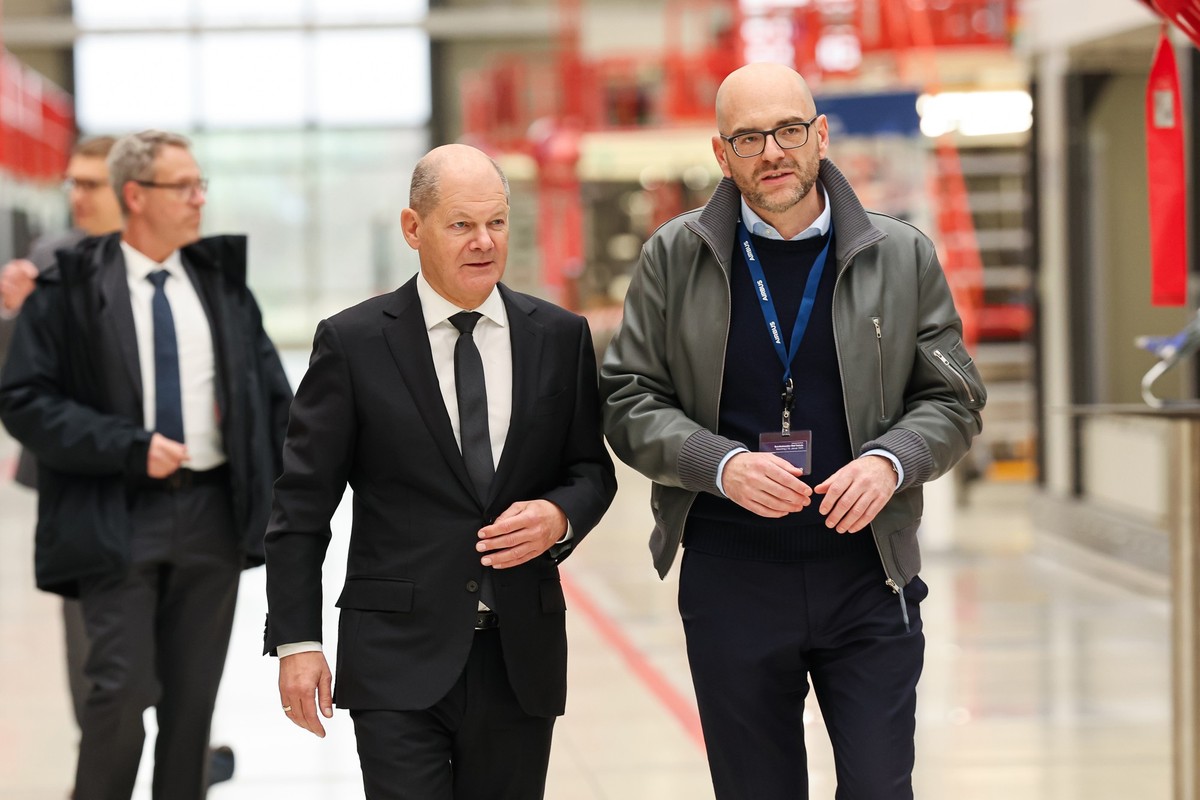 19.01.2024, Bayern, Manching: Bundeskanzler Olaf Scholz (SPD, M) geht beim Besuch des Airbus-Militärstandorts mit Thomas Pretzl (r), Betriebsratsvorsitzender bei Airbus, durch die Endmontage-Halle des ...