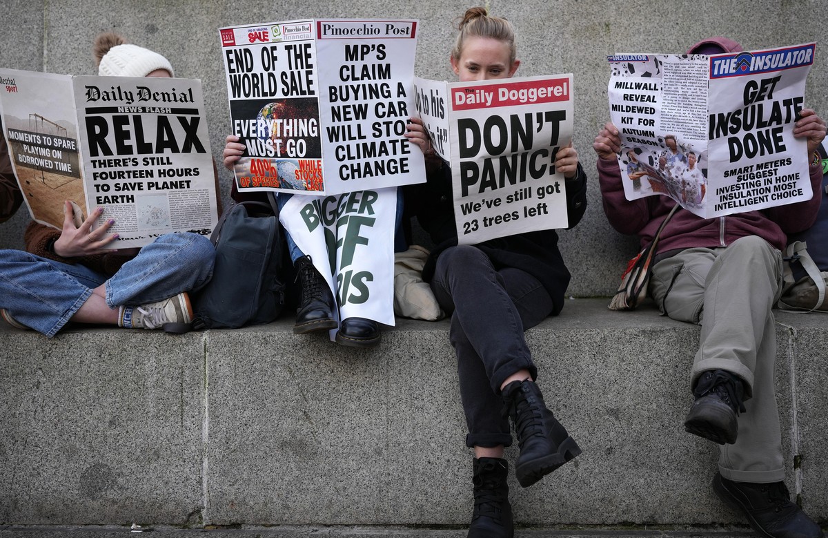 GLASGOW, SCOTLAND - NOVEMBER 07: Climate change activists read mock newspapers in George Square, Glasgow in support of victims of oil exploration and against fossil fuel investments in Africa during t ...