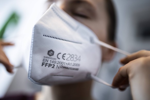 Eine Frau setzt eine FFP2-Maske auf, aufgenommen in Berlin, 15.01.2021. Aufgrund des sich noch immer ausbreitenden Corona-Viruses gibt es eine Diskussion ueber eine generelle Pflicht zum Tragen eines  ...