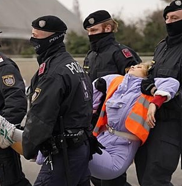 Klimaaktivistin Anja Windl wird von der Polizei von der Straße getragen, die sie zuvor blockiert hatte.