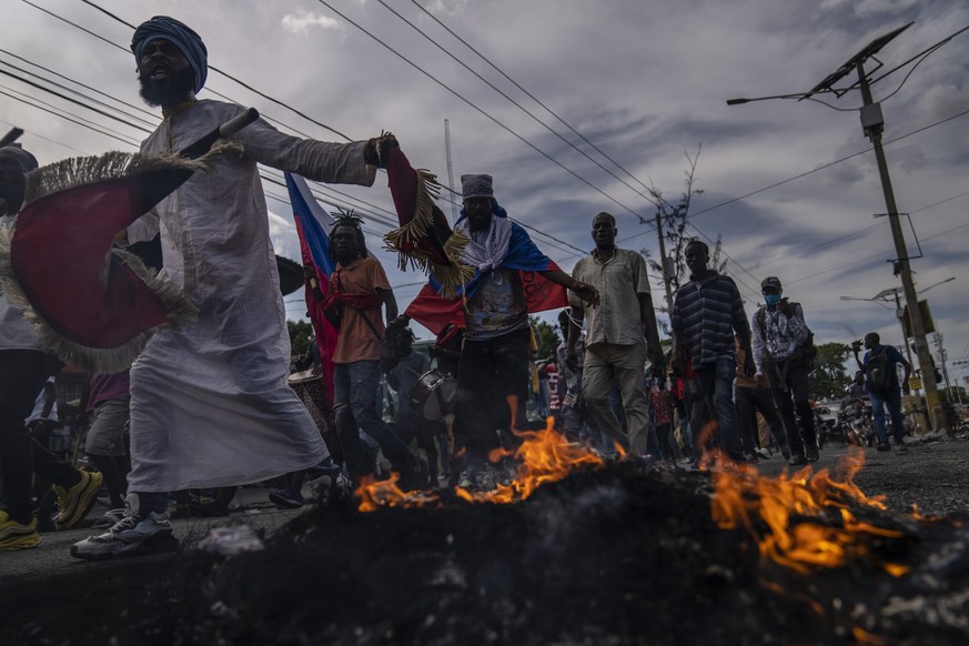 Protesters walk past a burning barricade during a protest against the government&#039;s request for an international military force, in Port-au-Prince, Haiti, Friday, Oct. 21, 2022. (AP Photo/Ramon Es ...