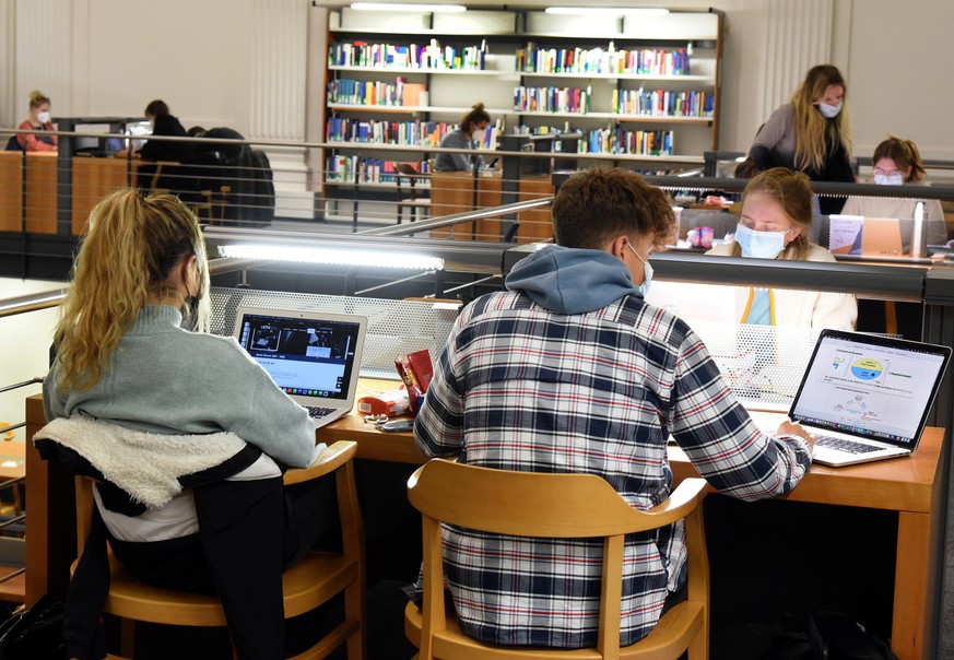 In der Universitätsbibliothek sitzen Studenten an mit Computern bestückten Tischen. Unter den aktuellen Rahmenbedingungen werden von den Studenten auch die Bibliotheken und andere Einrichtungen der Un ...