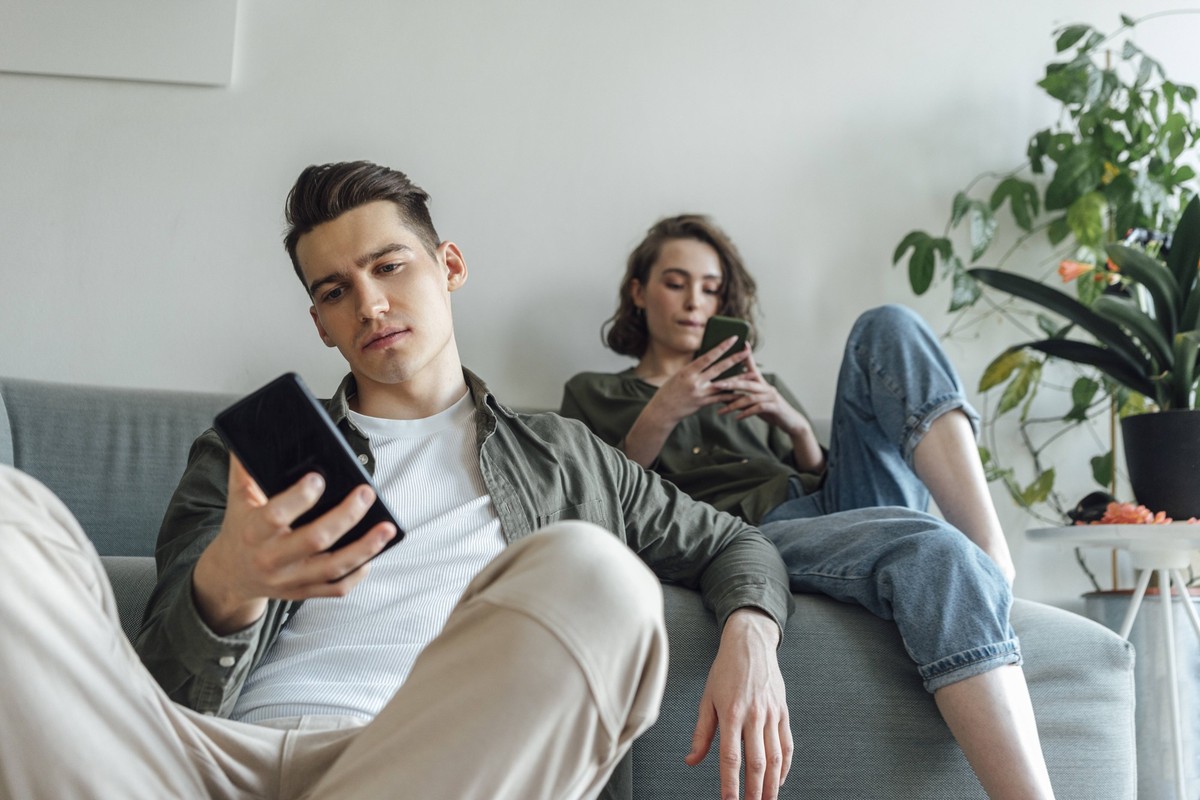 Young couple surfing net through smart phones in living room model released property released, VPIF05388