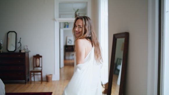 Sexy woman flirting camera at house closeup. Playful lady turning around posing at home interior portrait. Sensual girl in silk robe feeling joy at morning apartment. Positive people emotions concept