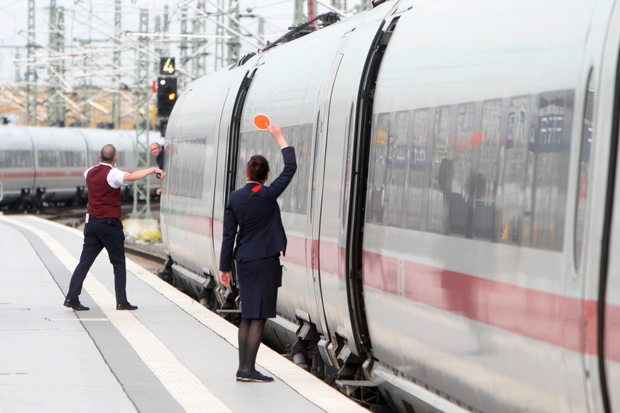 Die Zugbegleiter der deutschen Bahn geben dem Lokführer das Signal zur Weiterfahrt.
