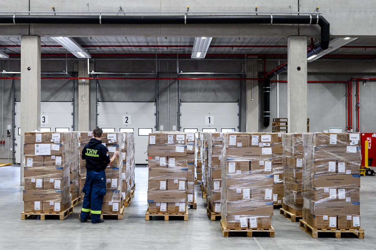 12.04.2022, Bayern, Elsenfeld: Ein Mitarbeiter des THWs kontrolliert die auf Paletten geladenen FFP2 Masken. Bayerns Innenstaatssekret�r Kirchner (CSU) besucht das neue Logistikzentrum der Bundesansta ...