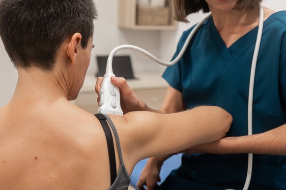 A healthcare worker applies a handheld ultrasound probe to a male patient s shoulder during a medical diagnostic exam Model Released HodeiUnzueta_ID18737_558266_047 Copyright: xHodeixUnzuetax