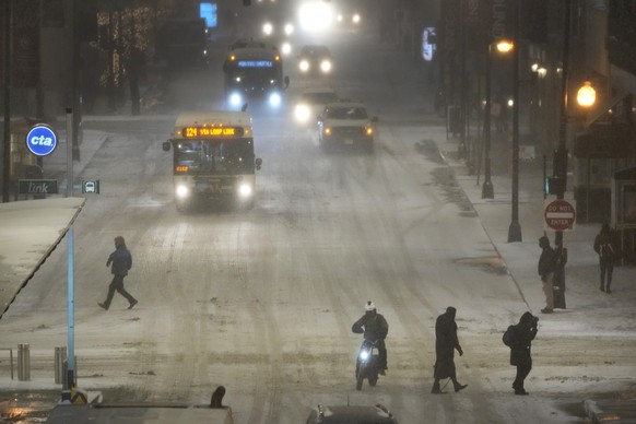 22.12.2022, USA, Chicago: Fußgänger gehen durch die glatten Straßen vom Bezirk Loop. Ein arktisches Sturmtief bringt über die Weihnachtstage drastische Temperaturstürze und extreme Kälte in die USA. F ...