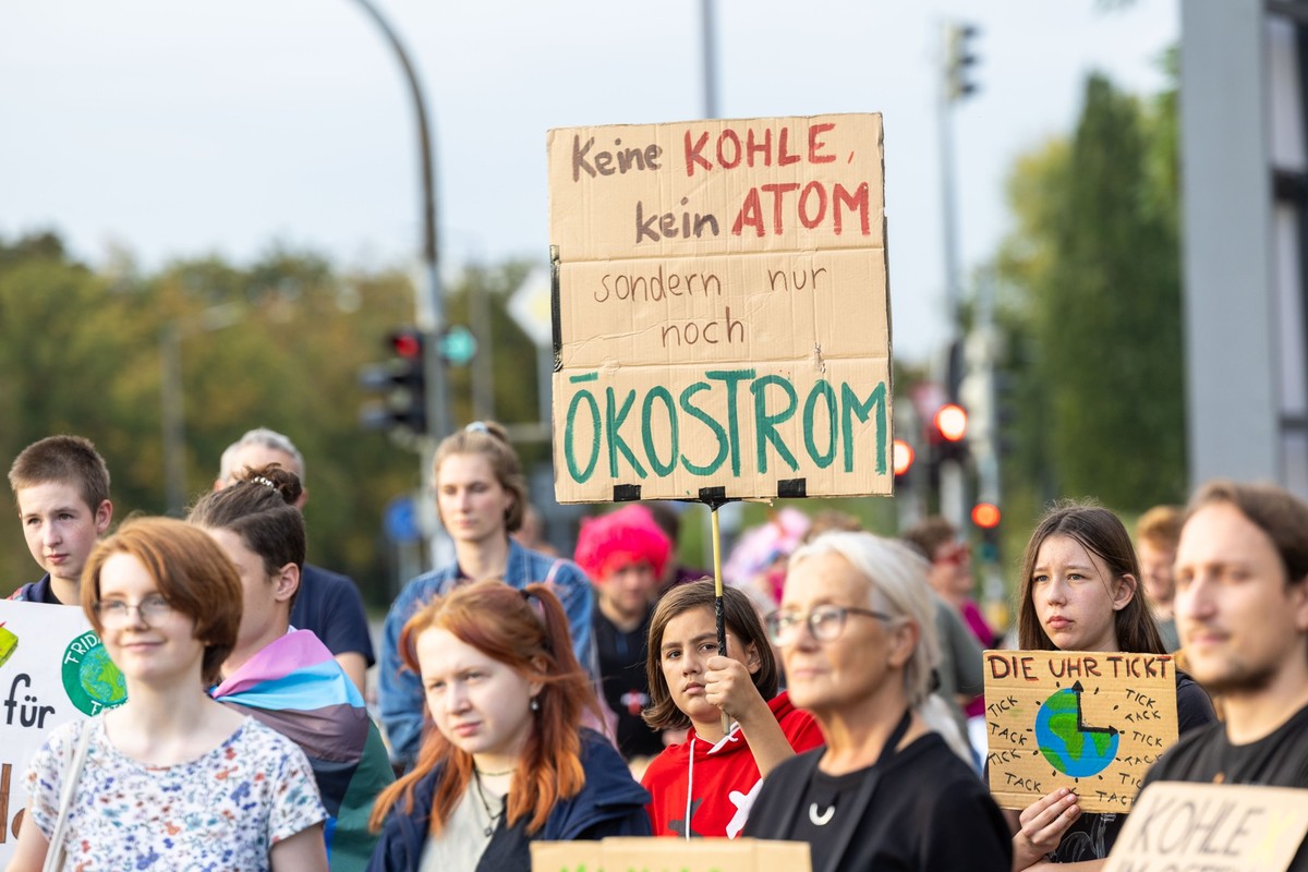 13.10.2023, Sachsen, Dresden: Eine junge Frau in einem roten Shirt (Mitte) hält beim Protest Fridays for Future Dresden vor der Sächsischen Staatskanzlei ein Schild mit der Aufschrift &quot;Keine Kohl ...