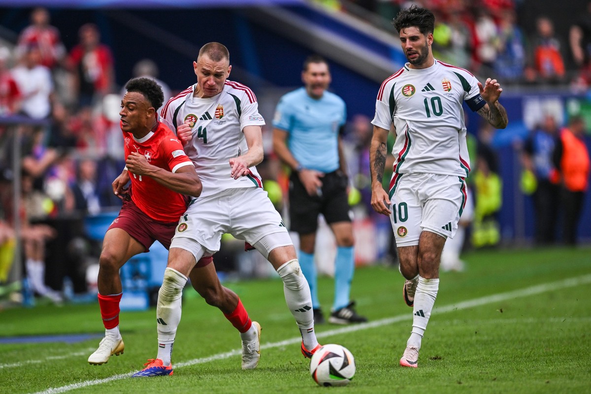 15.06.2024, Nordrhein-Westfalen, K�ln: Fu�ball, EM, Ungarn - Schweiz, Vorrunde, Gruppe A, Spieltag 1, K�ln Stadion, Dan Ndoye aus der Schweiz (l) k�mpft gegen Ungarns Attila Szalai (M) und Ungarns Dom ...