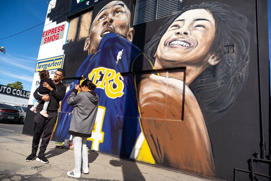 January 28, 2020, Studio City, California, USA: Maria Home captures a photo of her daughter Lena Colon and her father Uziel Colon in front of a mural in tribute to Kobe Bryant and his daughter, Gigi,  ...