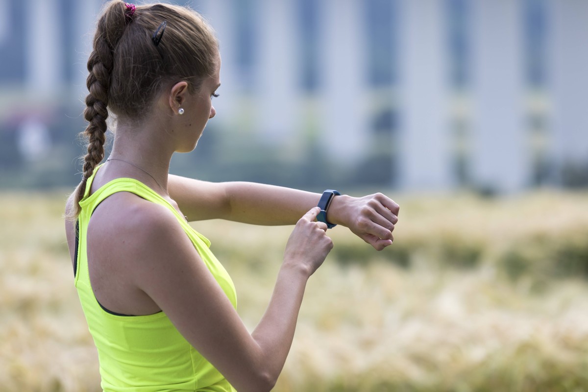Junge Frau beim Joggen, Dauerlauf, kontrolliert ihre Vitaldaten auf einer Fitness Uhr, Fitness Tracker, Pulsschlag, Herzfrequenz Anzahl der Schritte, Strecke, Zeit, Kalorienverbrauch, *** Young woman  ...