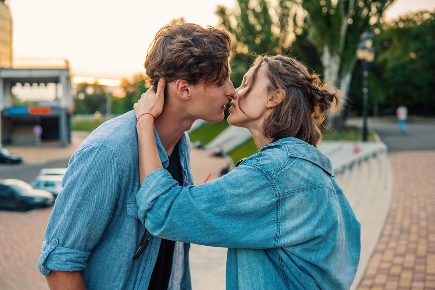 Lovely young hipster couple dating during summer sunset. they wear jeans clothes. they are kissing