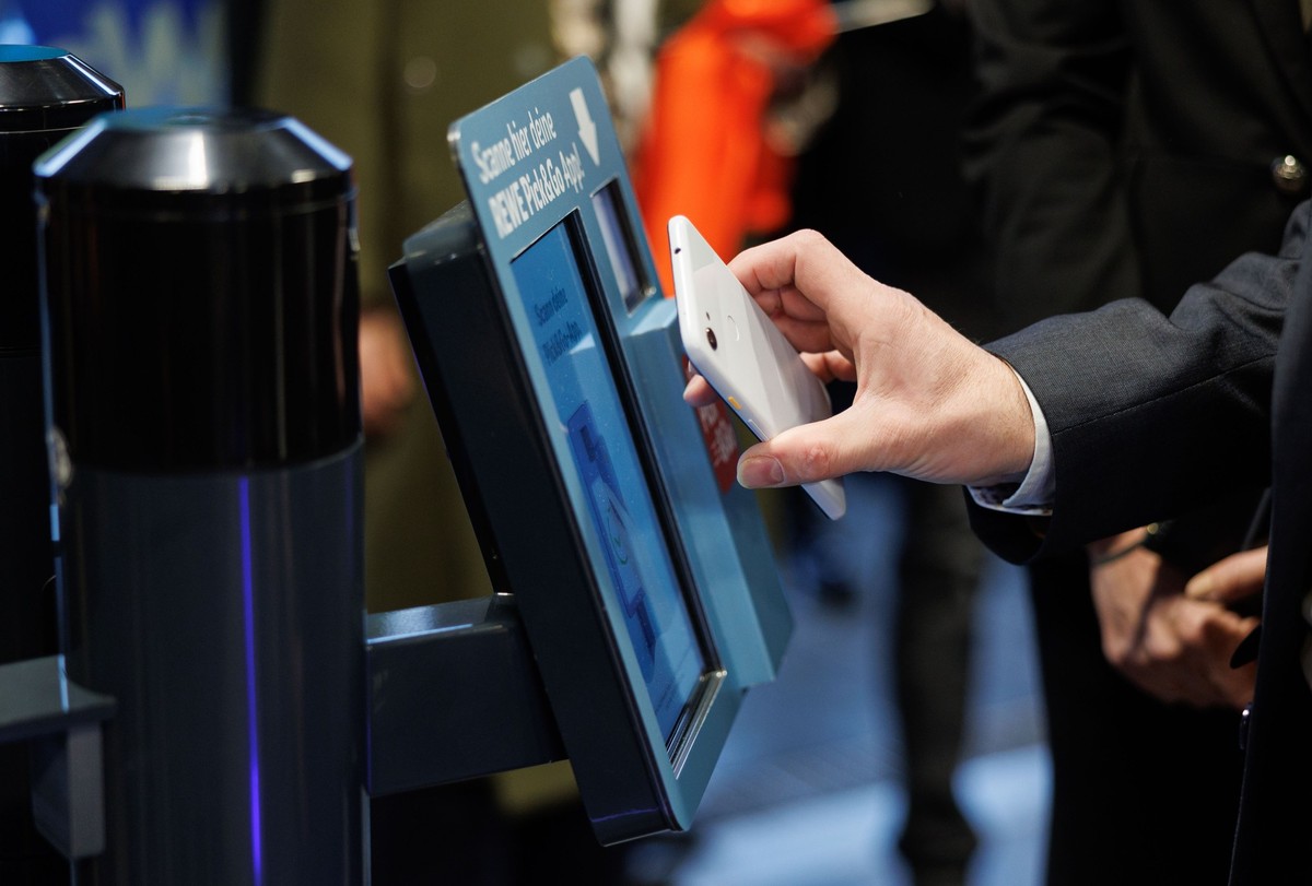 14.12.2022, Bayern, München: Der Bayerische Wirtschaftsminister Hubert Aiwanger (Freie Wähler) scannt ein Handy während der Eröffnung der ersten vollautomatische Rewe Pick&amp;Go Filiale in München. F ...