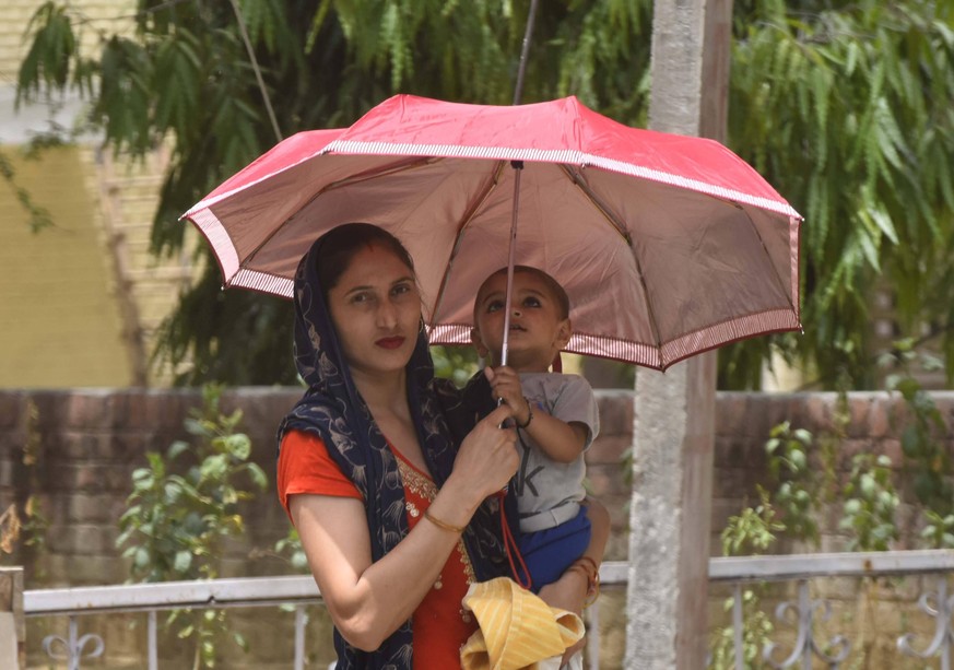 GURUGRAM, INDIA - MAY 16: A pedestrian with an umbrella on a hot summer afternoon on May 16, 2022 in Gurugram, India. The record-breaking spell of the intense heatwave continues in parts of North and  ...