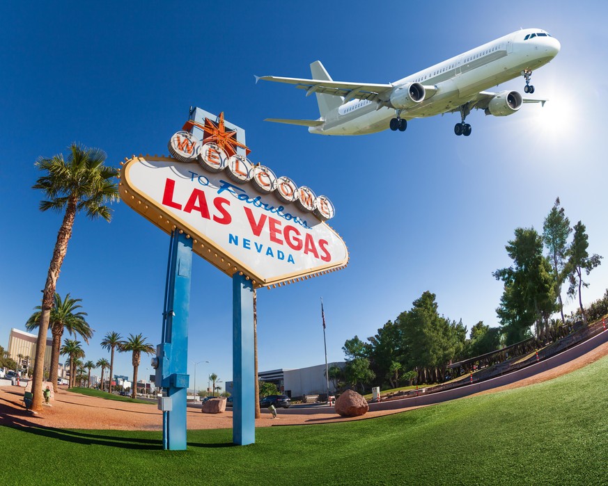 Welcome sign to Las Vegas with airplane flying in the sky during summer sunny day in Vegas, Nevada, USA