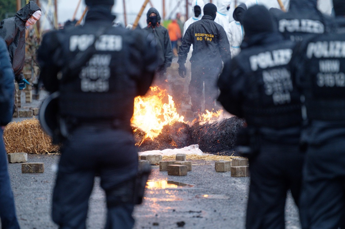 02.01.2023, Nordrhein-Westfalen, Lützerath: Während die Polizei Vorbereitungen zur geplanten Räumung des Dorfes Lützerath trifft, bauen Aktivisten (hinten) Barrikaden auf und stecken diese in Brand. F ...