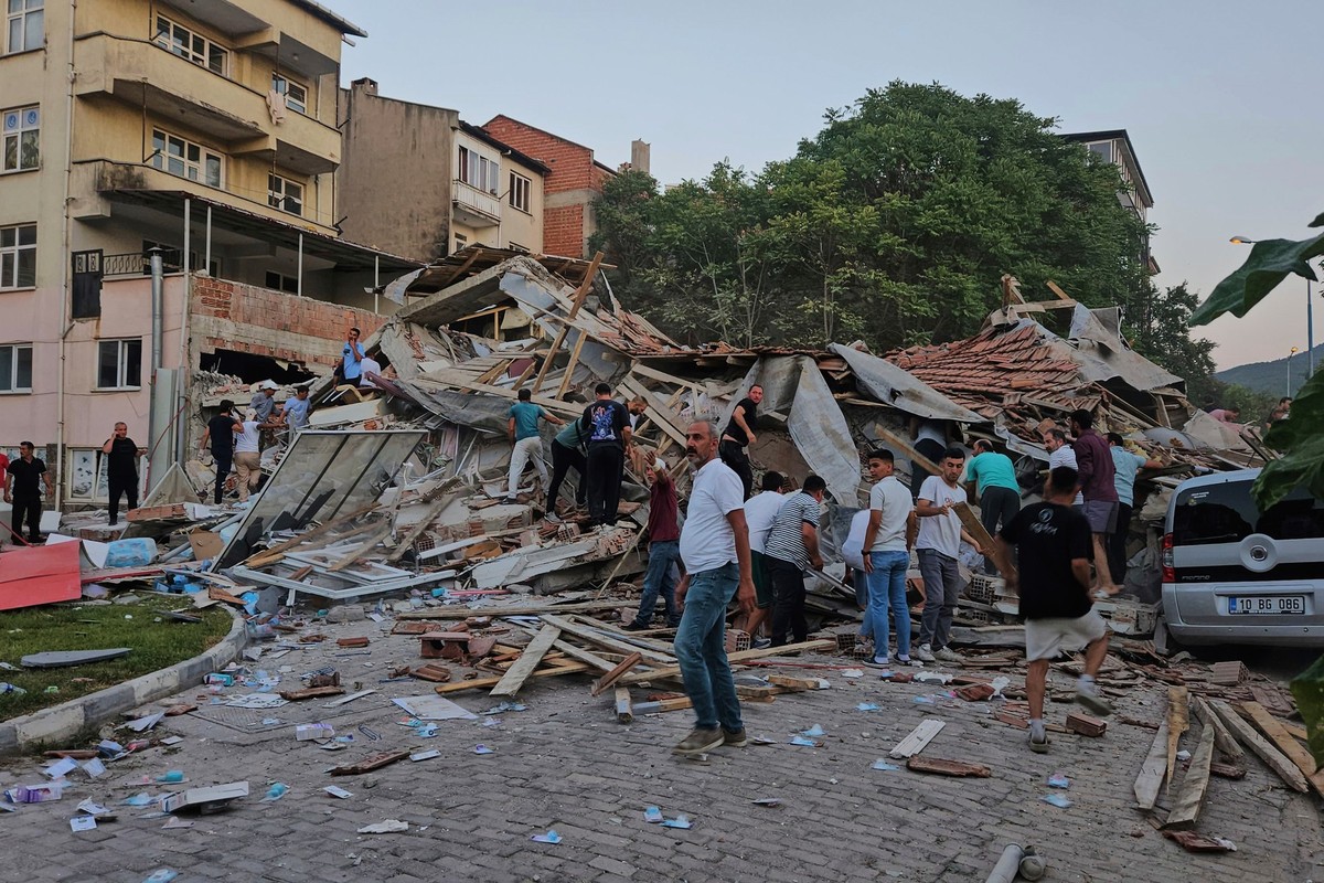 10.08.2025, Türkei, Sindirgi: Menschen beseitigen die Trümmer eines eingestürzten Gebäudes nach einem Erdbeben in Sindirgi in der Westtürkei. Foto: Bahadir Demirceviren/IHA/AP/dpa +++ dpa-Bildfunk +++