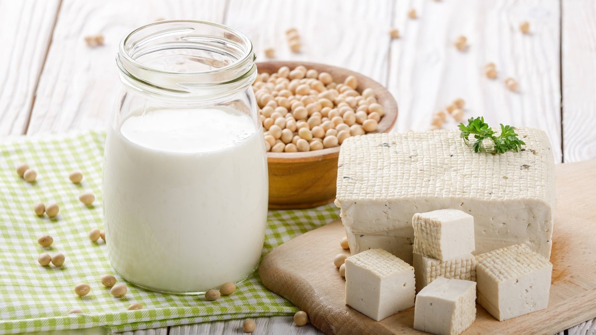 Non-dairy alternatives Soy milk or yogurt in mason jar and tofu on white wooden table with soybeans in bowl aside Non-dairy alternatives Soy milk or yogurt in mason jar and tofu on white wooden table  ...