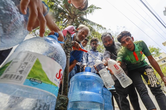 ARCHIV - 22.04.2024, Bangladesch, Dhaka: Menschen holen sich Trinkwasser aus einer Wasserleitung am Straßenrand, während der landesweit anhaltenden Hitzewelle. (zu dpa: «Wie im Backofen: Rekord-Hitzew ...