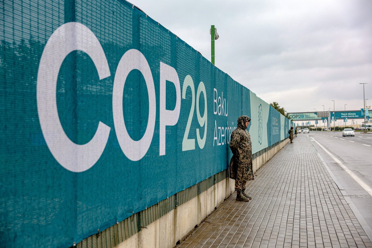 November 10, 2024, Baku, Azerbaijan, Azerbaijan: A soldier assigned as security, in front of COP29 signage which lines the front of the Baku Olympic Stadium site on a rainy day, the day before the ope ...