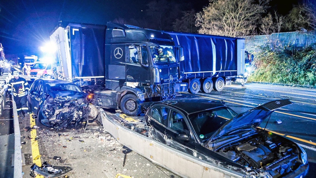 30.11.2024, Nordrhein-Westfalen, Hagen: Ein Lastwagen steht auf der Autobahn 1 bei Hagen an der Unfallstelle neben beschädigten Autos. Nach einer Chaosfahrt über mehrere Autobahnen hat die Polizei in  ...