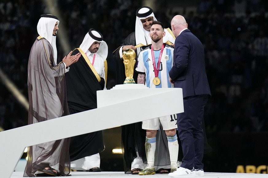 The Emir of Qatar Sheikh Tamim bin Hamad Al Thani puts on a cloak on Argentina's Lionel Messi after he won the World Cup final soccer match between Argentina and France at the Lusail Stadium in Lusail ...