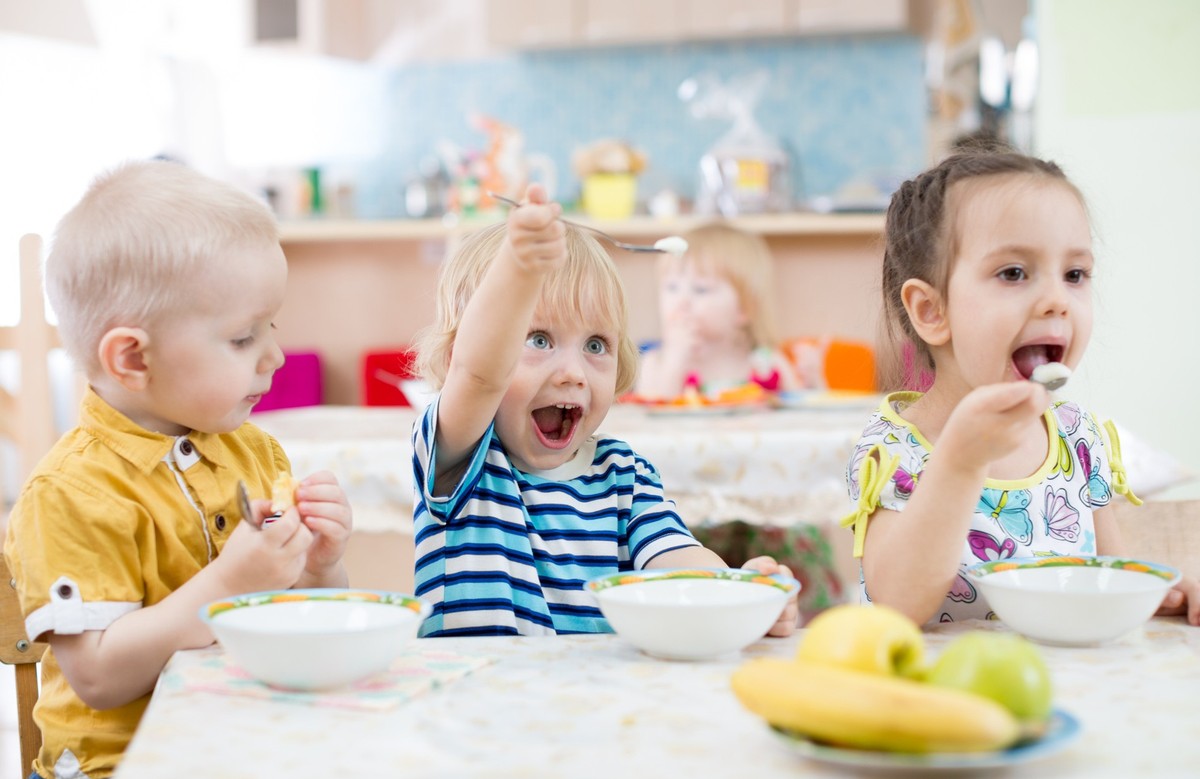 funny kids group eating in kindergarten