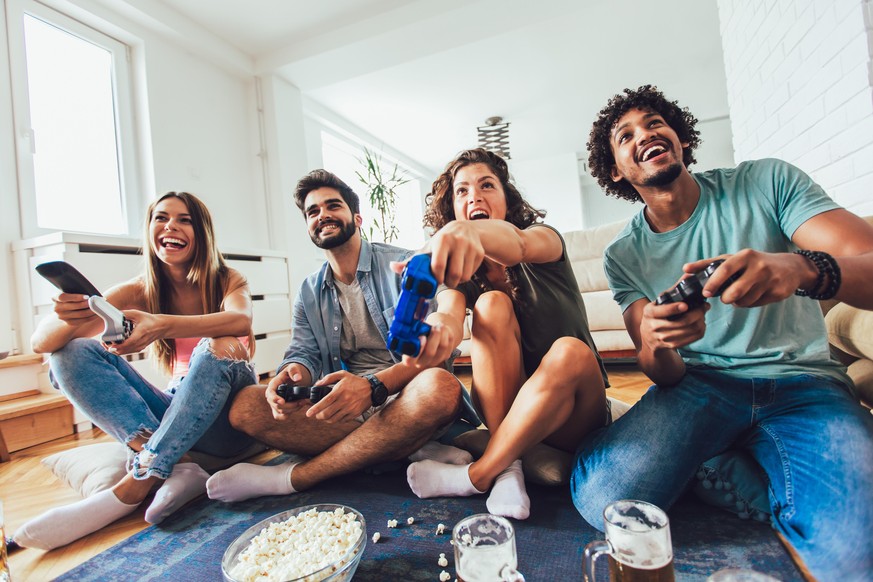 Happy group of young friends playing video games at home.