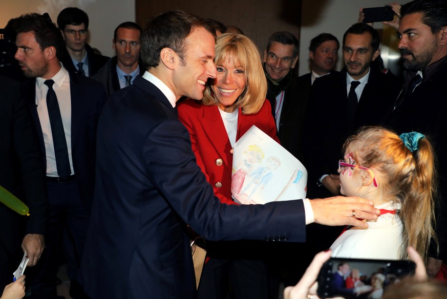 French President Emmanuel Macron and his wife Brigitte Macron receive a drawing as a present from a girl during the Christmas Party for the children of Elysee Palace&#039;s employees at the Gobelins M ...