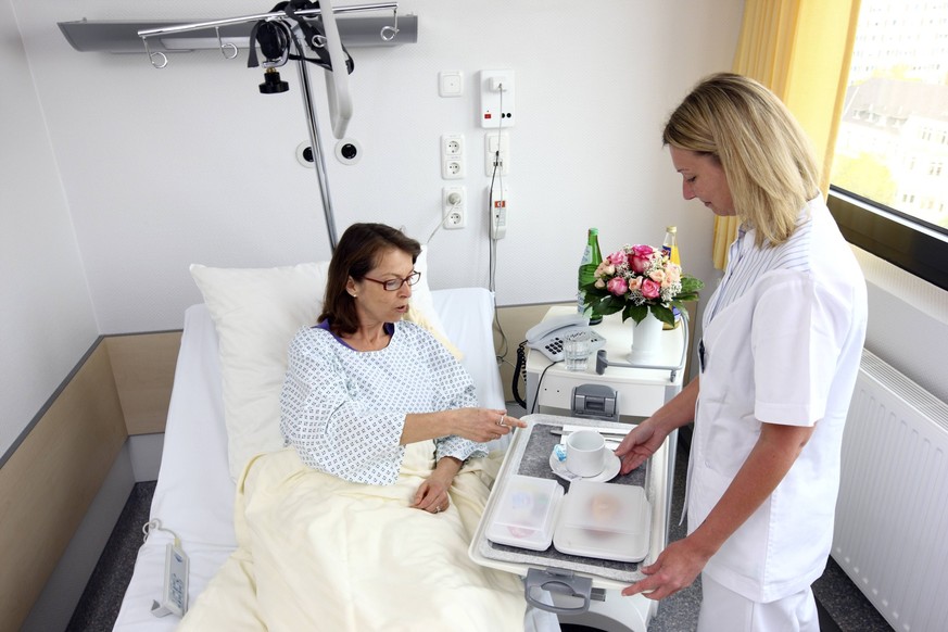 Bildnummer: 55555596 Datum: 28.06.2011 Copyright: imago/Jochen Tack
Medizin, Krankenhaus. Patientin in einem Einzelzimmer, im Krankenbett. Krankenschwester bringt eine Mahlzeit auf einem Tablett. Kran ...