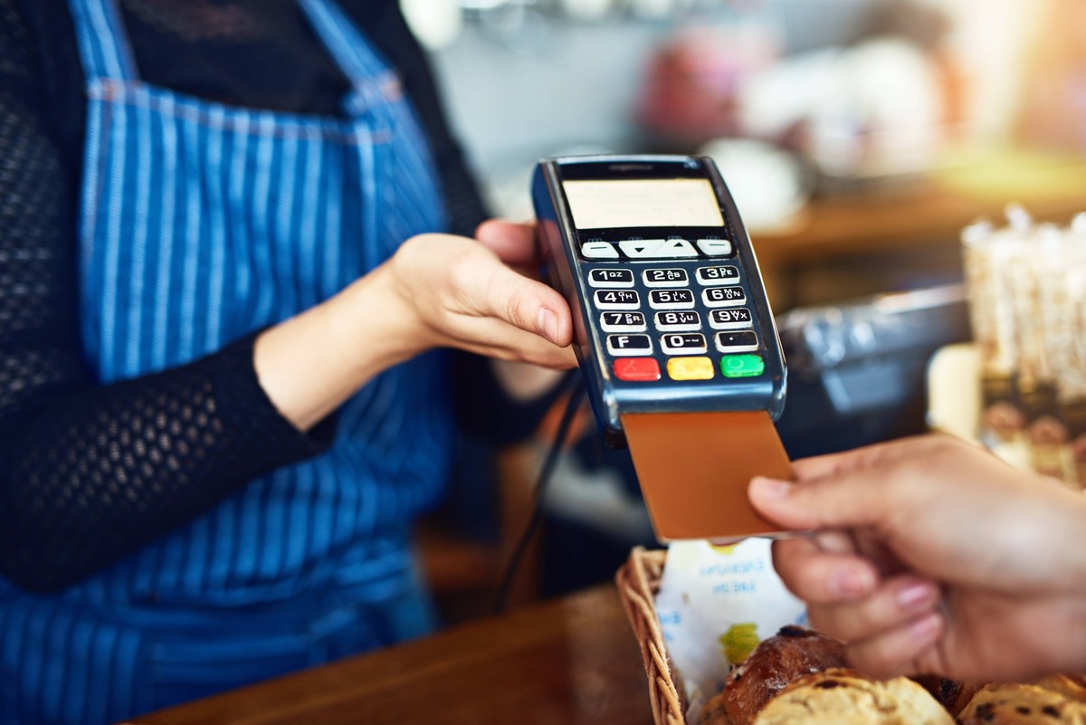 Credit card payment, cafe and hands with a machine at a restaurant for a service or food. Bakery, pay and a customer paying or buying a product at a coffee shop with a transaction from a worker. model ...